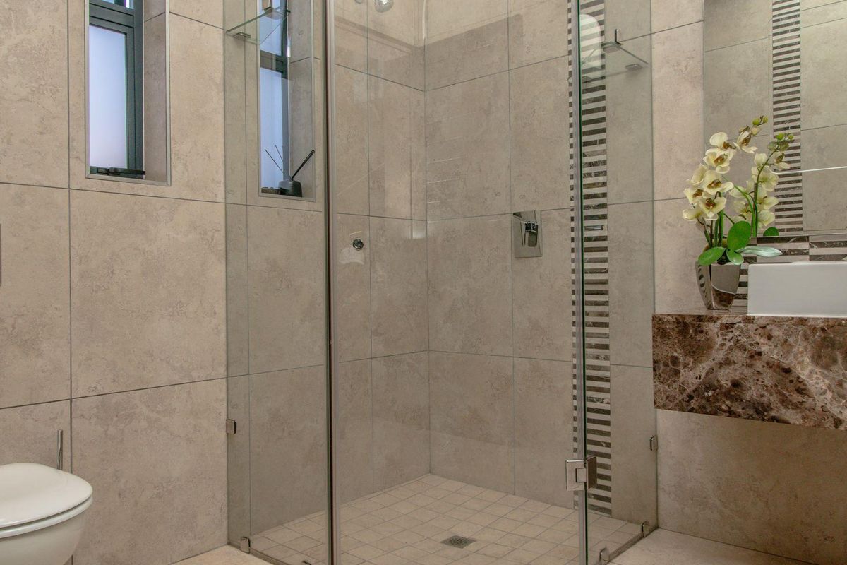 Modern bathroom featuring a glass-enclosed shower, wall-mounted toilet, and a stone-topped vanity with a contemporary basin.