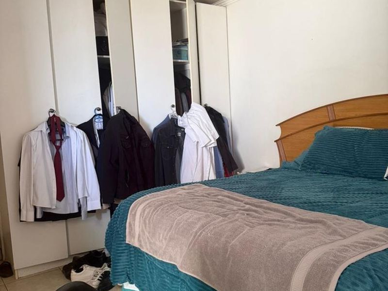 A bedroom featuring built-in wardrobes and tiled flooring, providing functional storage space.