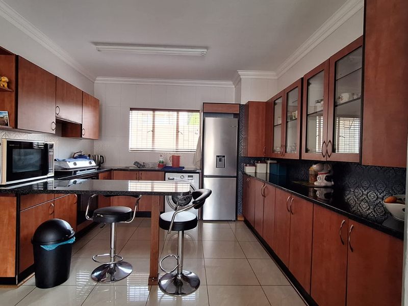 A functional kitchen featuring extensive wooden cabinetry, granite countertops, a built-in breakfast bar, and tiled flooring.