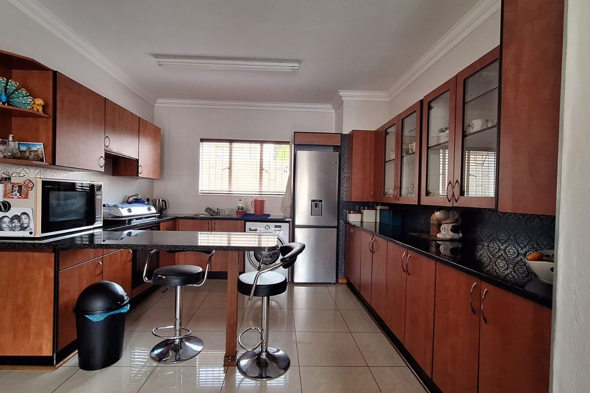 A functional kitchen featuring extensive wooden cabinetry, granite countertops, a built-in breakfast bar, and tiled flooring.