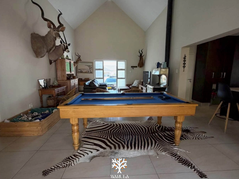 Spacious living area featuring a high vaulted ceiling, tiled flooring, and a prominent freestanding fireplace, offering a bright and open atmosphere.