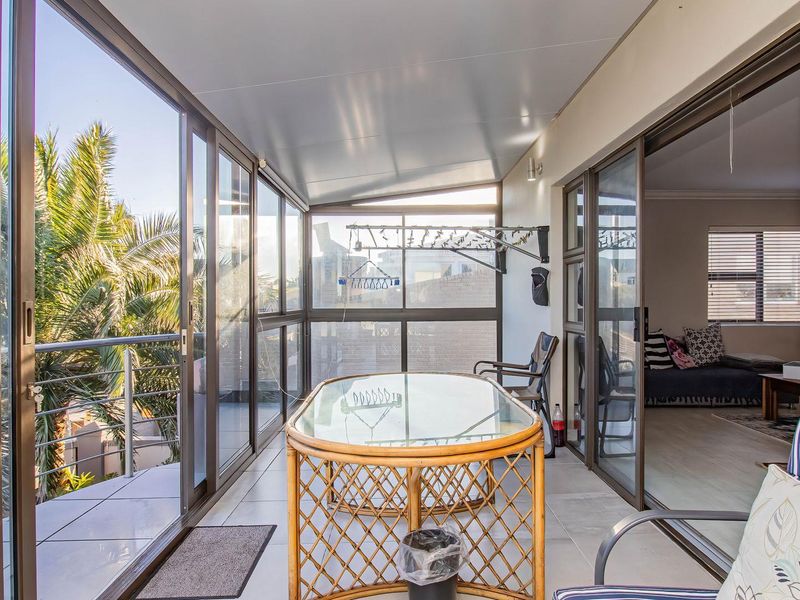 A covered balcony featuring large sliding glass doors, tiled flooring, and a wall-mounted drying rack, offering an airy transition between indoor and outdoor living spaces.