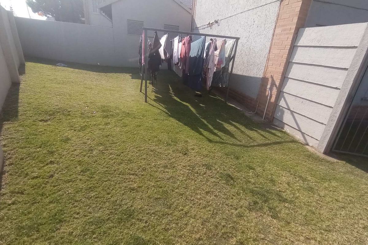 A private rear garden area featuring a lawn and perimeter boundary walls.
