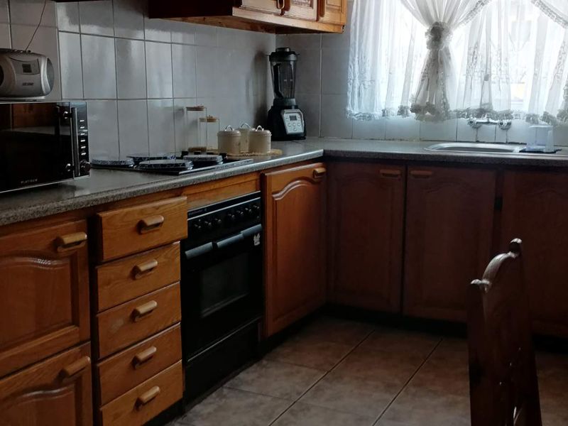 A functional kitchen featuring traditional wooden cabinetry, laminate countertops, a built-in oven, and a tiled backsplash with a double sink.