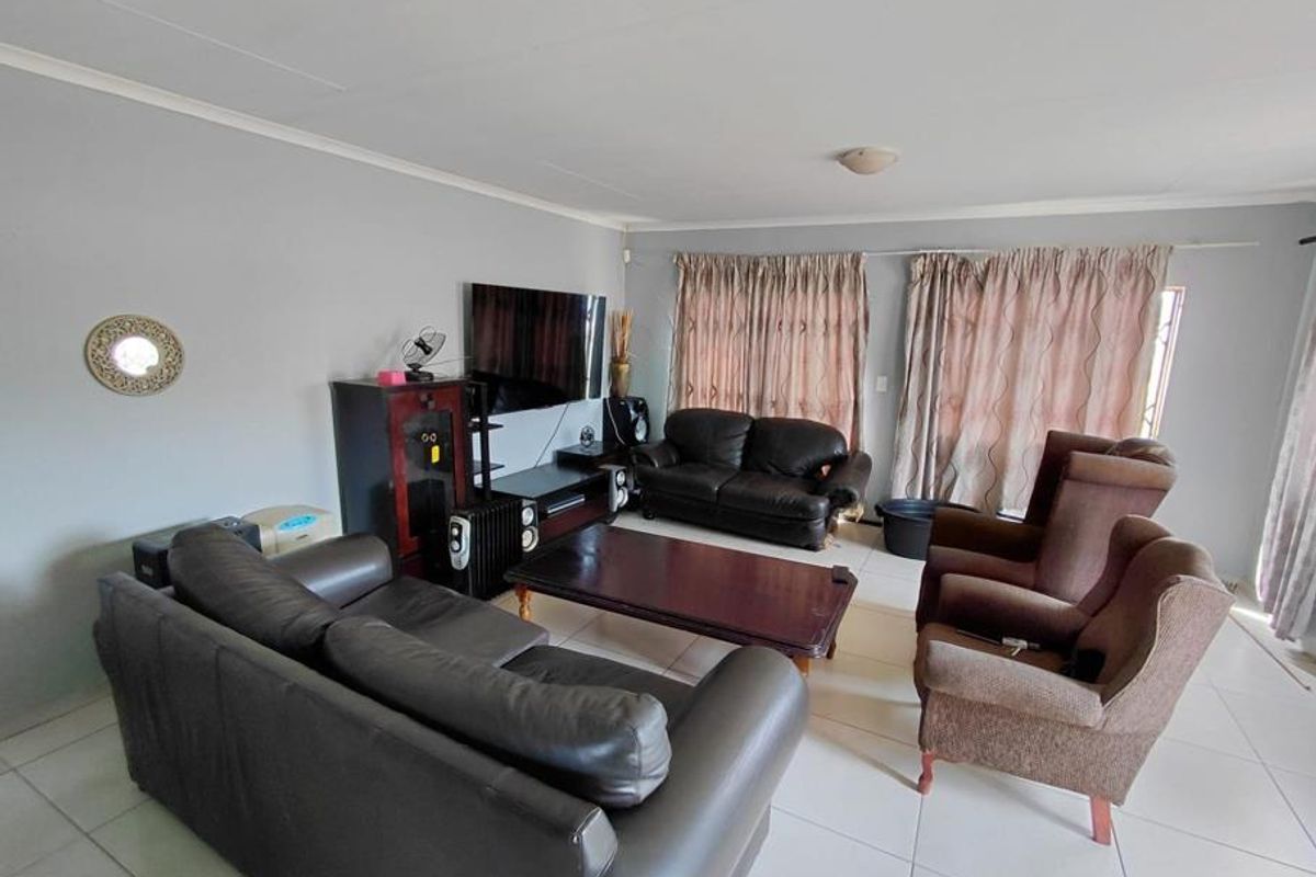 A spacious living room featuring neutral tiled flooring and classic cove cornicing, providing a functional and comfortable base for family relaxation.