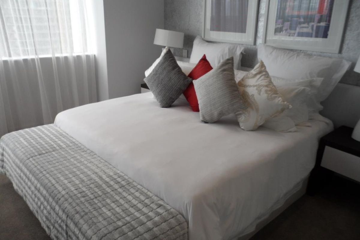 A well-maintained bedroom featuring neutral wall finishes, carpeted flooring, and large windows allowing for natural light.