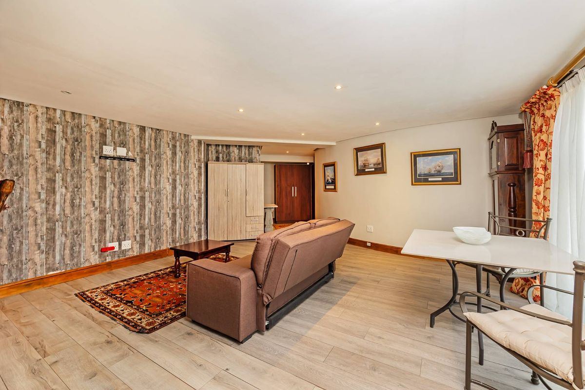 A living room featuring laminate flooring, recessed downlights, and built-in storage cupboards, offering a functional and neutral living space.