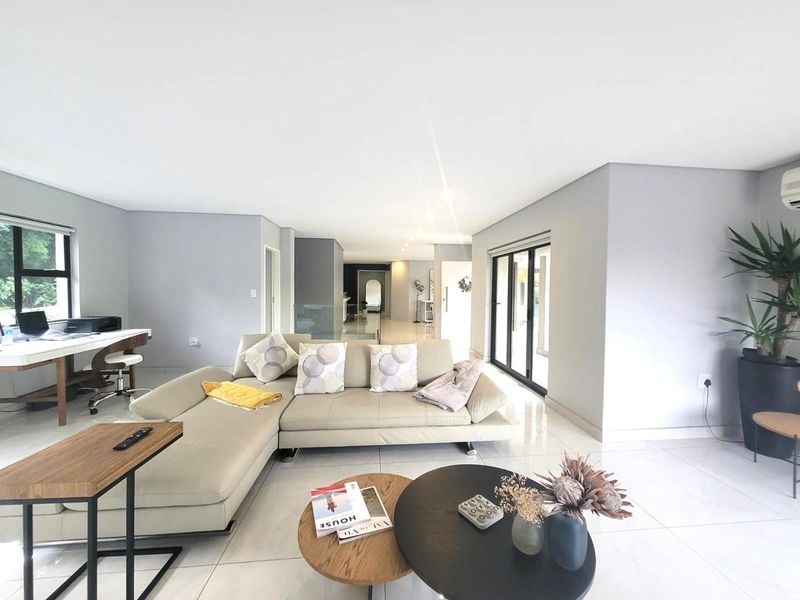 Spacious open-plan living area featuring neutral tiled flooring, modern recessed lighting, and large sliding glass doors providing ample natural light.