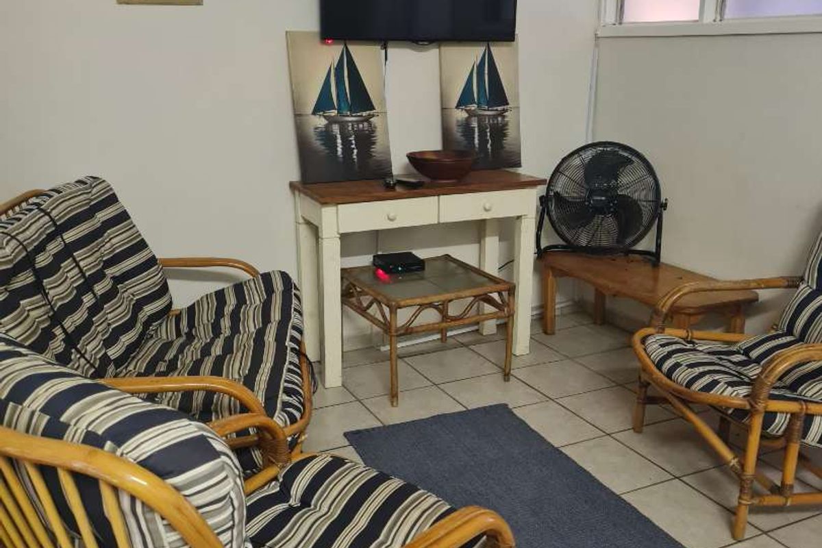 A living area featuring tiled flooring and a wall-mounted television, offering a functional space for relaxation.