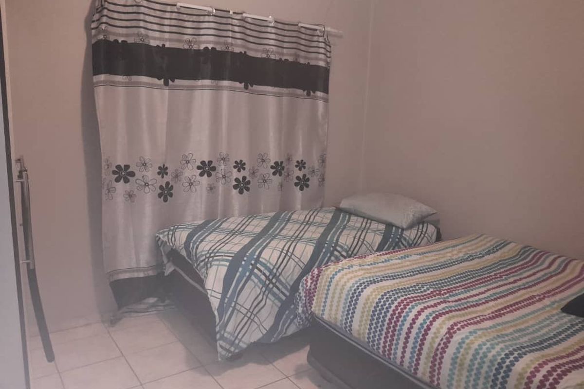 A bedroom featuring tiled flooring and a curtain rod, providing a functional space for sleeping arrangements.