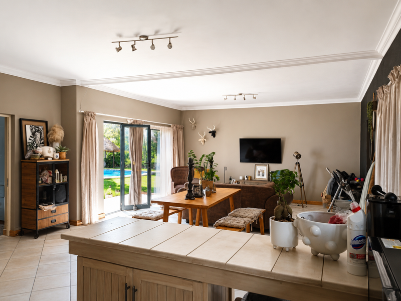 Spacious open-plan living area featuring tiled floors, track lighting, and direct access to the outdoor pool area through sliding glass doors.