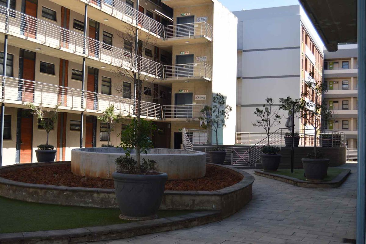A view of the apartment complex courtyard featuring paved walkways, a central fountain, and multi-story residential units with metal balcony railings.