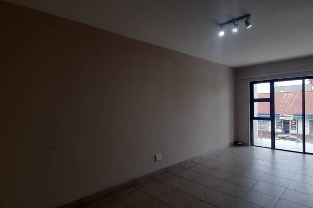 An empty, open-plan living area featuring tiled flooring, neutral walls, and large sliding glass doors leading to an exterior space.