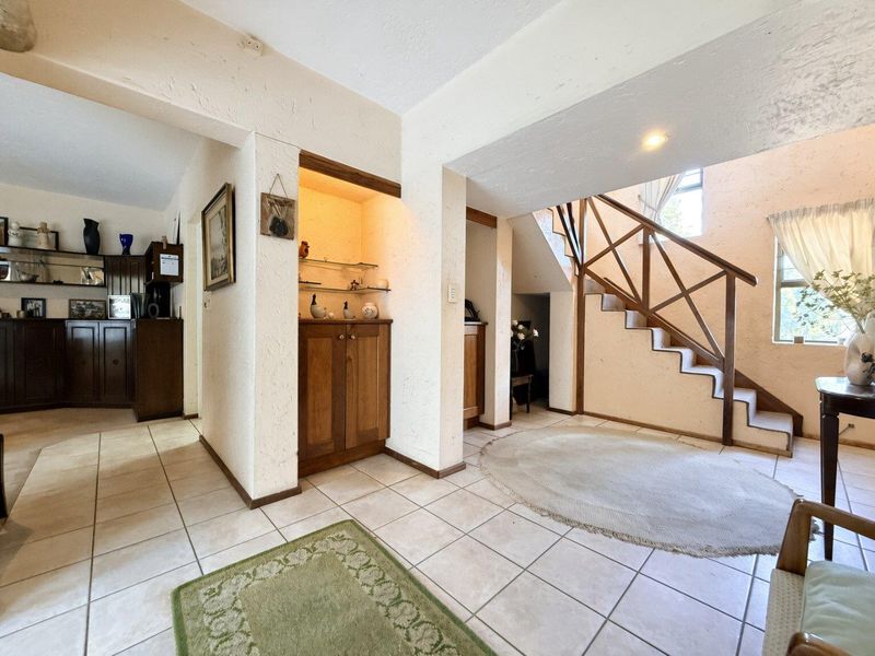 Spacious entrance hall featuring tiled flooring, built-in cabinetry, and a wooden staircase leading to the upper level.