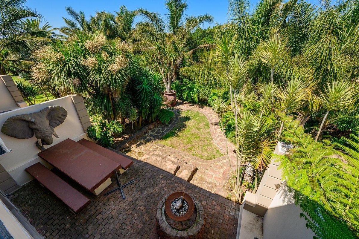 A private rear garden featuring a paved patio area, stone pathway, and lush established landscaping, providing a tranquil outdoor retreat.