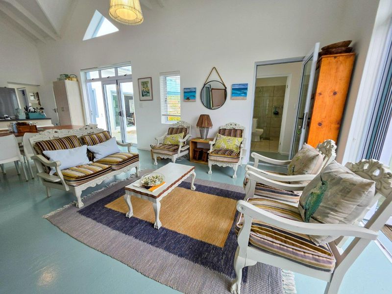 Spacious open-plan living area featuring a vaulted ceiling, skylight, and direct access to the patio through glass sliding doors.