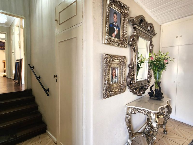 A welcoming entrance hall featuring built-in storage cabinetry, a staircase with a handrail, and tiled flooring leading into the home.