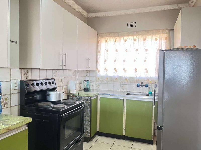 A functional kitchen featuring built-in cabinetry, a stainless steel sink, and a freestanding stove, offering potential for modernization and cosmetic updates.