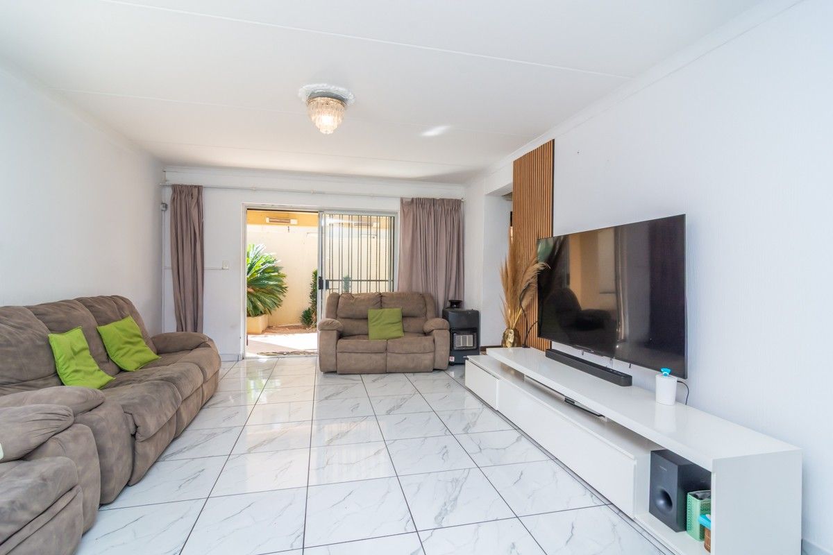 Bright living room featuring marble-look floor tiles, decorative wall paneling, and a sliding glass door providing access to the outdoor patio area.