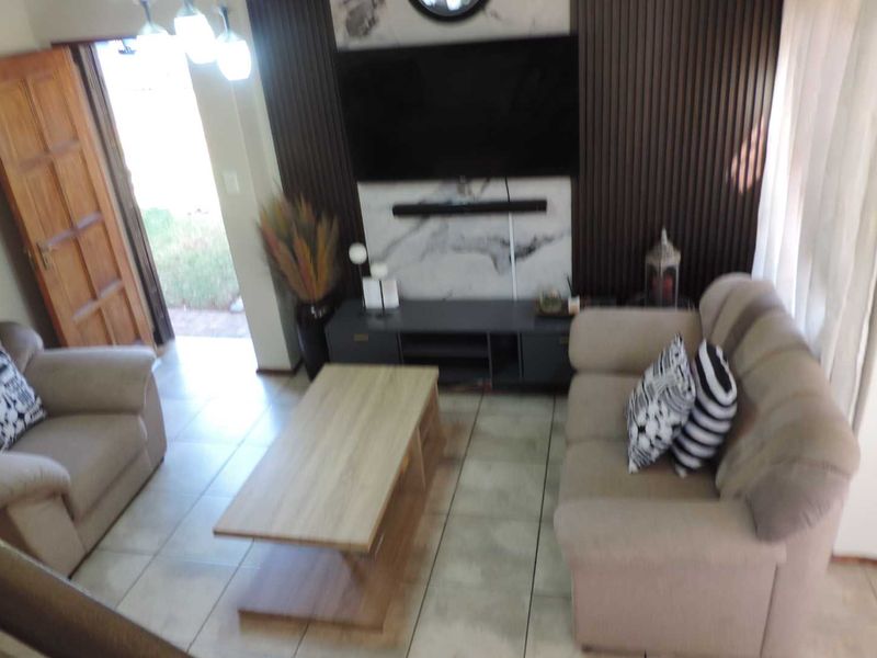 A living room featuring tiled flooring, a timber entrance door, and a modern feature wall with marble-look cladding and vertical timber paneling.