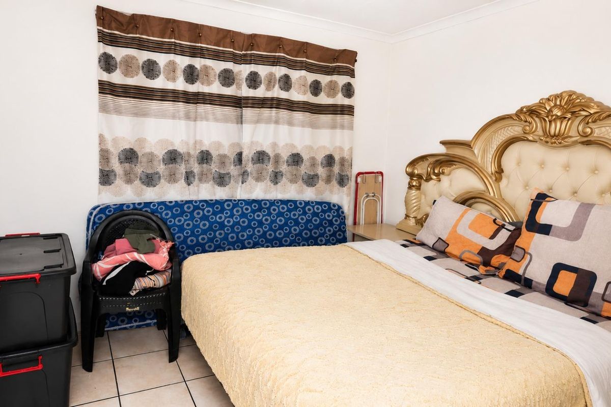 A bedroom featuring tiled flooring and a window with fitted curtain tracks.
