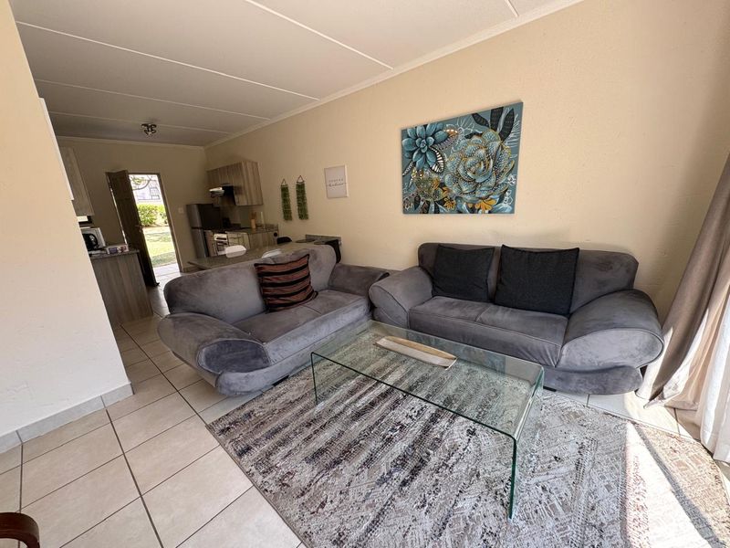 Open-plan living area featuring tiled flooring and a connected kitchen space with built-in cabinetry and countertops.