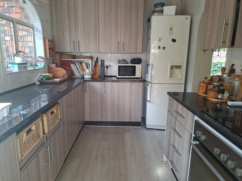 Functional kitchen featuring wood-look laminate cabinetry, granite countertops, built-in oven, and a classic arched window providing natural light.