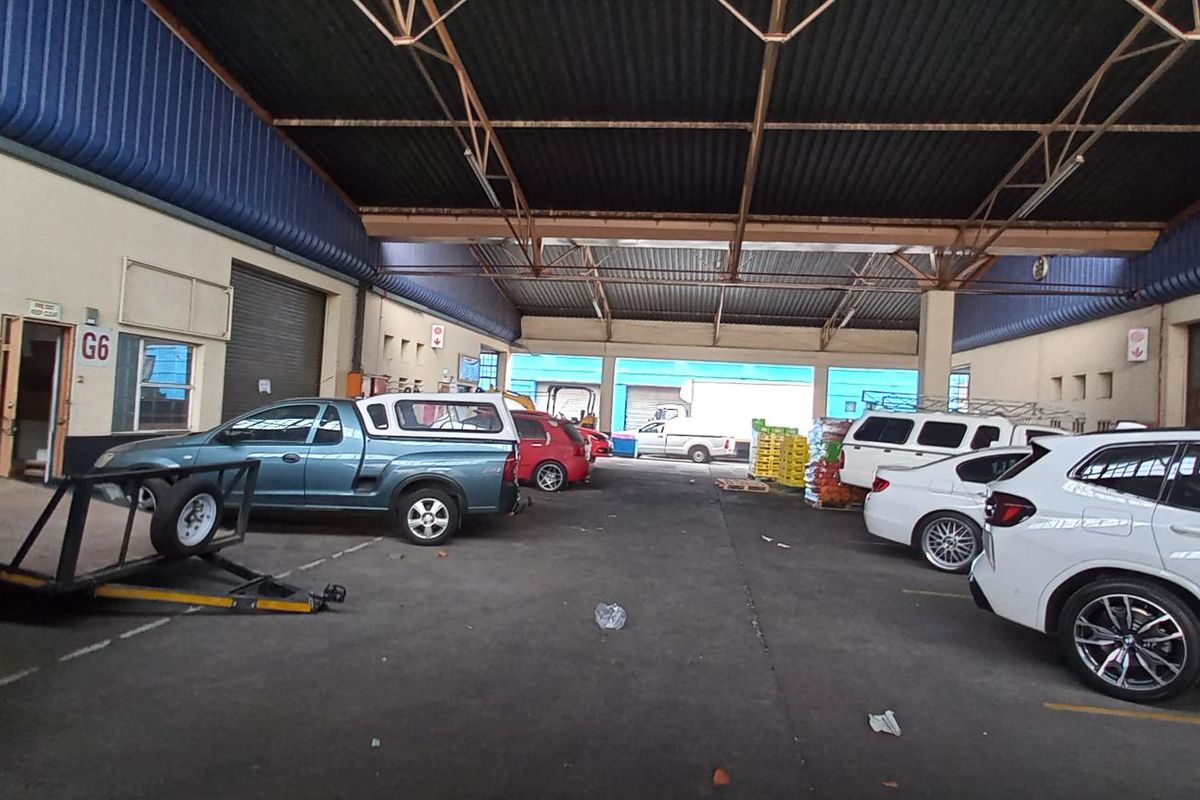 Spacious industrial garage facility featuring high-clearance steel roof trusses, concrete flooring, and multiple roller shutter access points suitable for vehicle storage or light industrial use.