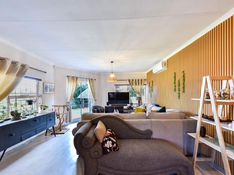 A bright living room featuring modern slatted timber wall paneling, a split-system air conditioner, and sliding glass doors providing access to the outdoor area.