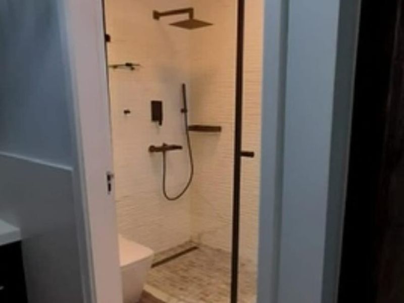 A modern, well-appointed bathroom featuring a walk-in shower with a glass screen, contemporary fixtures, and clean tiled finishes.