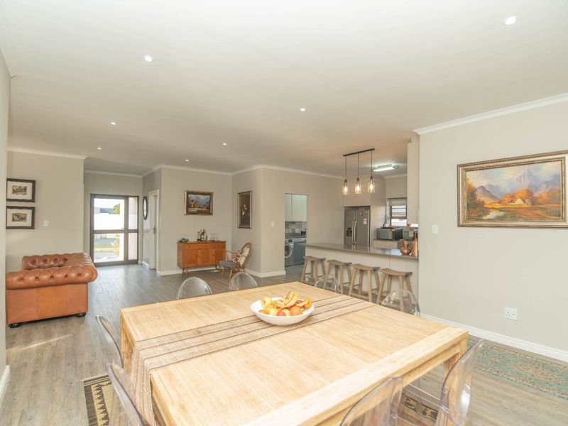 Spacious open-plan living and dining area featuring modern laminate flooring, recessed lighting, and a functional breakfast bar connecting to the kitchen.