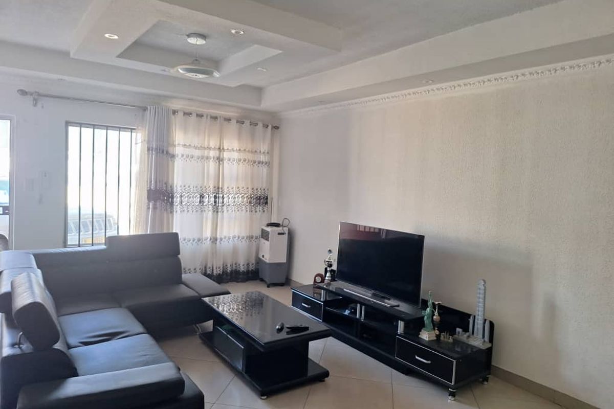 A living room featuring tiled flooring, a recessed ceiling with integrated lighting, and a security gate at the entrance.