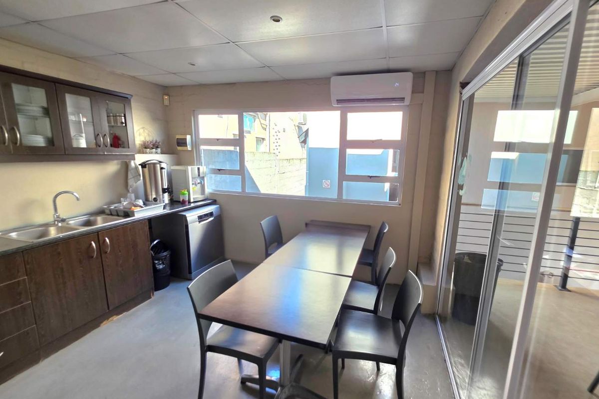 A functional kitchenette area featuring built-in cabinetry, a stainless steel sink, and an integrated air conditioning unit, suitable for office or staff use.