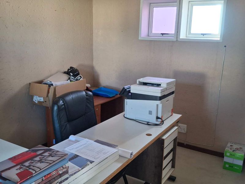 A functional office space featuring dual windows and neutral wall finishes, suitable for a professional workspace or study area.