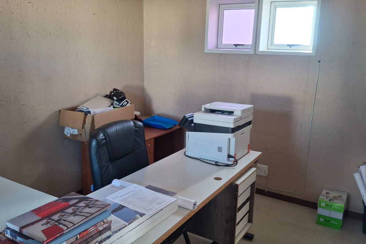 A functional office space featuring dual windows and neutral wall finishes, suitable for a professional workspace or study area.