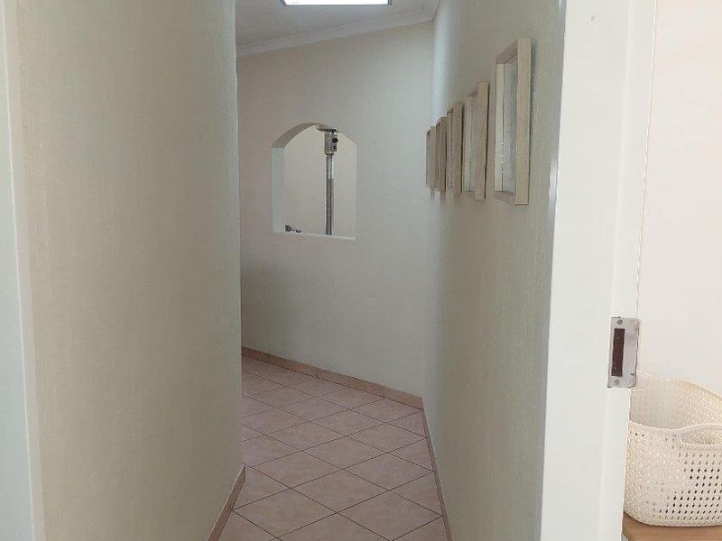 A bright, tiled hallway featuring a skylight and an interior archway, providing a clean and neutral transition space between rooms.