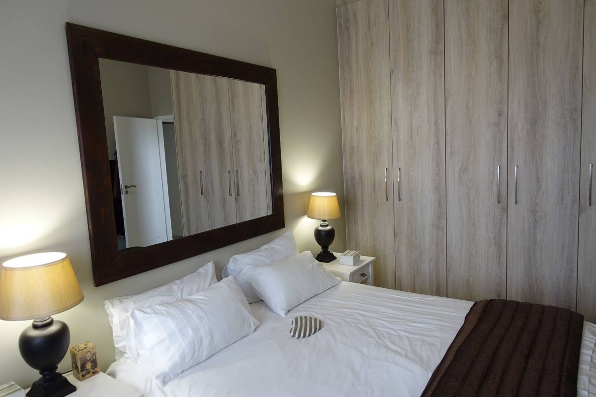 A well-maintained bedroom featuring built-in wooden cabinetry and a large wall-mounted mirror.