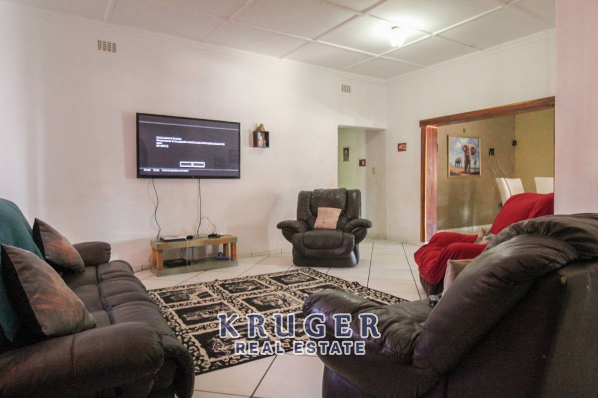 A spacious living room featuring tiled flooring and a ceiling with exposed paneling, providing a functional and comfortable family living area.