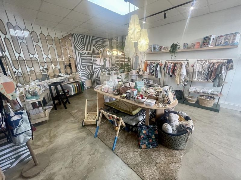 A well-maintained retail space featuring polished concrete floors, modern track lighting, and built-in wall shelving, currently utilized as a boutique shop.
