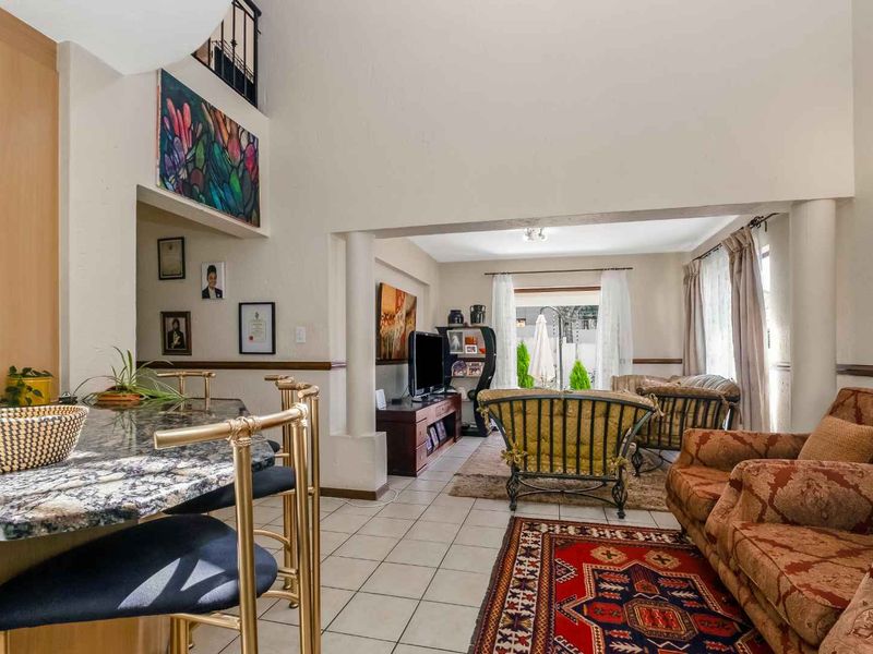 Spacious open-plan living area featuring tiled floors, a granite breakfast bar, and high ceilings with direct access to the outdoor patio.