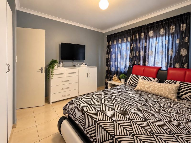 A well-maintained bedroom featuring tiled flooring, built-in wardrobe storage, and neutral wall finishes, offering a clean and functional living space.