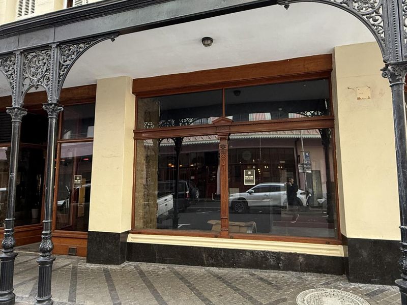 Street-level retail frontage featuring classic timber-framed display windows and ornate cast iron columns under a covered walkway.