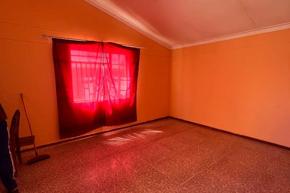 An empty bedroom featuring terrazzo flooring and a vaulted ceiling, awaiting updates to the wall finishes and lighting.