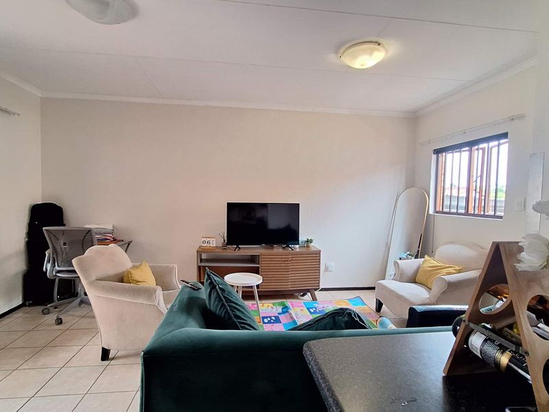 A bright living room featuring tiled flooring, security bars on windows, and neutral wall finishes, offering a functional and comfortable living space.