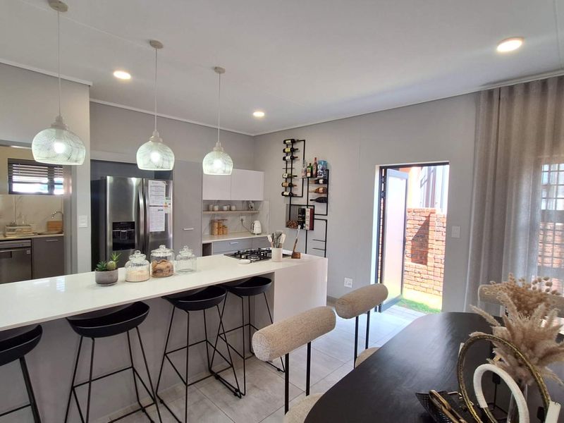 Modern open-plan kitchen featuring a central island with gas hob, sleek cabinetry, and seamless flow to the dining area and outdoor space.
