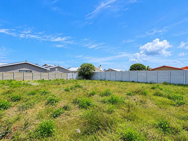 A vacant residential plot featuring a level grassed area enclosed by precast concrete boundary walls, situated within an established residential neighbourhood.