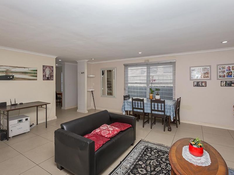 Spacious open-plan living and dining area featuring neutral tiled flooring, recessed lighting, and large windows with venetian blinds.