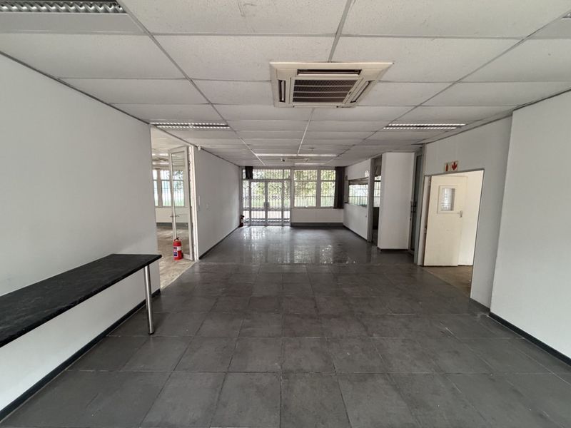 Spacious open-plan office area featuring tiled flooring, suspended ceilings with integrated air conditioning, and secure access points.