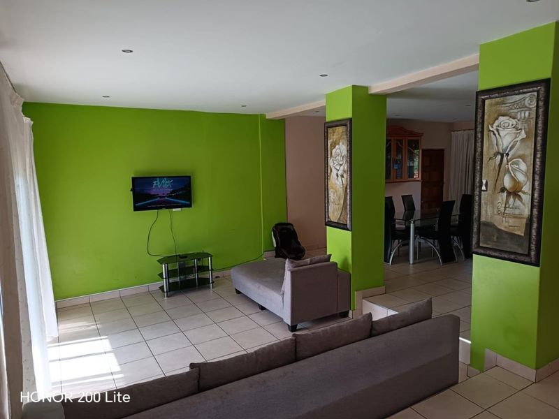 Open-plan living and dining area featuring ceramic floor tiles, recessed lighting, and a structural column, providing a versatile space for family living.