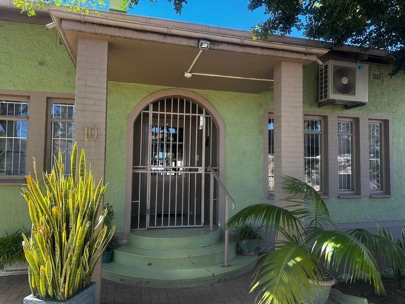 Front entrance of a mixed-use property featuring a covered porch, security gate, and exterior air conditioning unit.